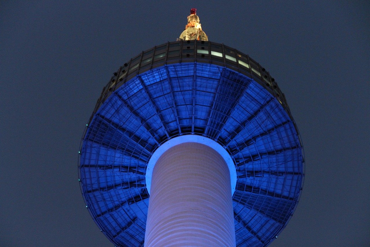 N Seoul Tower lit up in blue light at night, seen from directly below