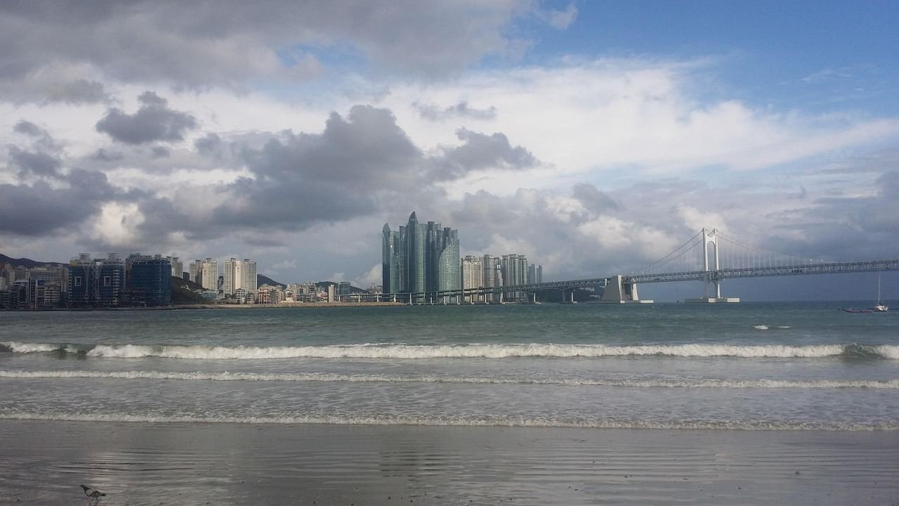 Gwangalli Beach during the day with the skyline and Gwangan Bridge beyond the sand
