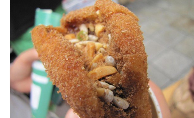 A seed-and-nut-filled hotteok pastry cut open at a Korean street food stall