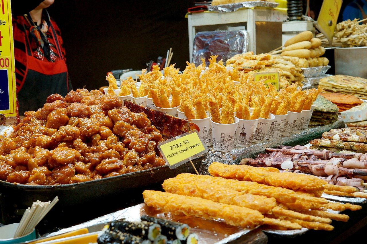 Assorted fried Korean street food skewers and gimbap at a market stall