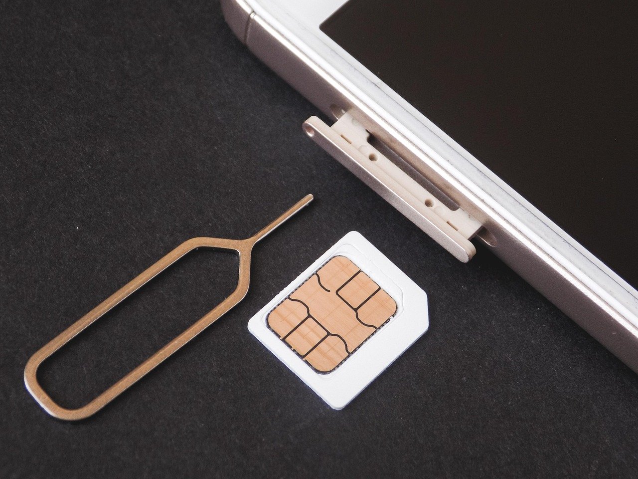 SIM card being removed from a smartphone tray with an ejector pin