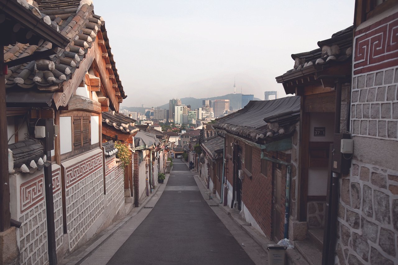 Quiet hanok alley in Bukchon Hanok Village with N Seoul Tower visible in the distance