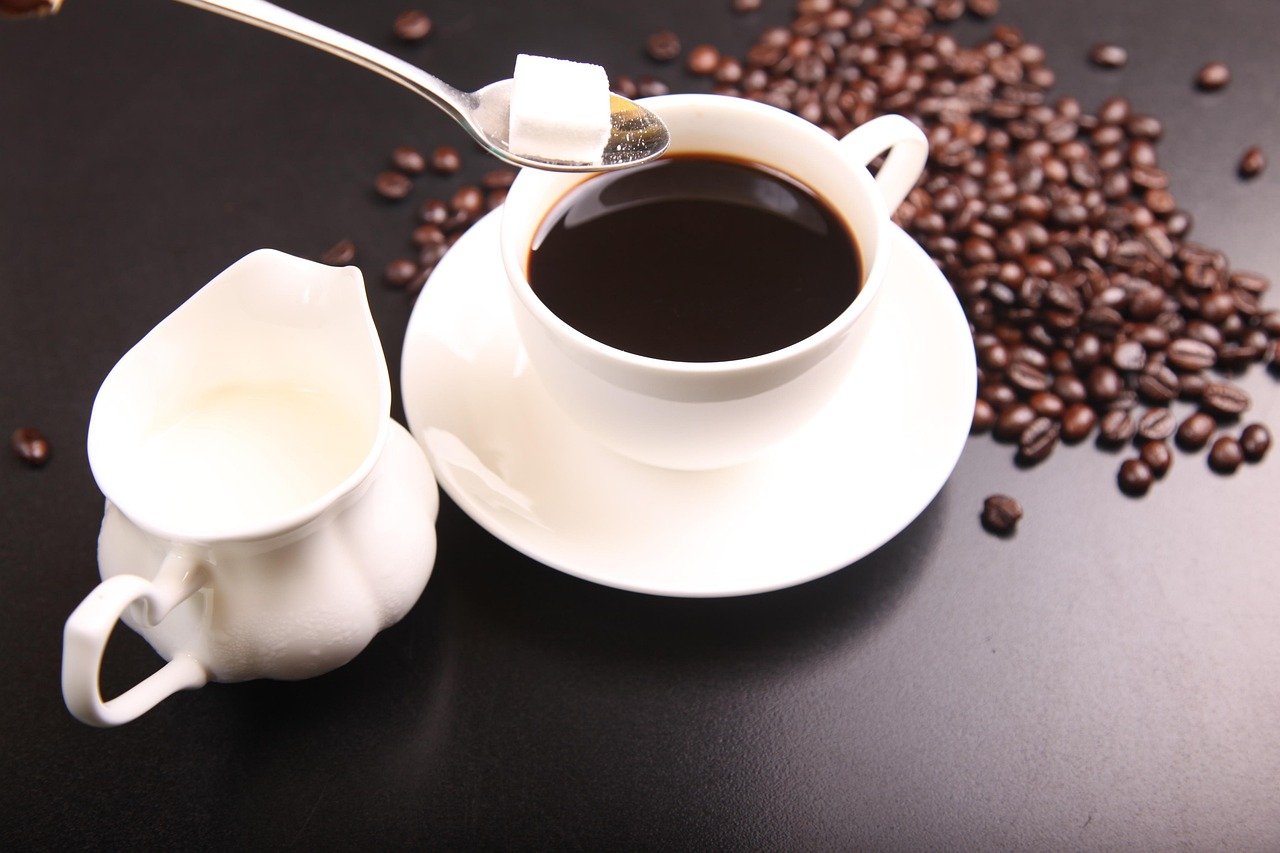 Cup of black coffee with sugar cube and coffee beans