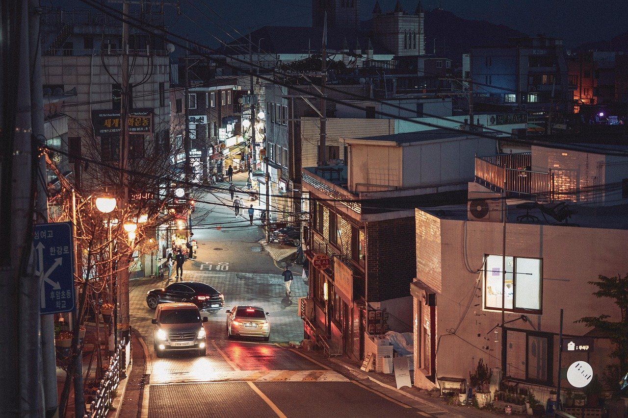 Quiet residential street in Korea at night with streetlights and parked cars
