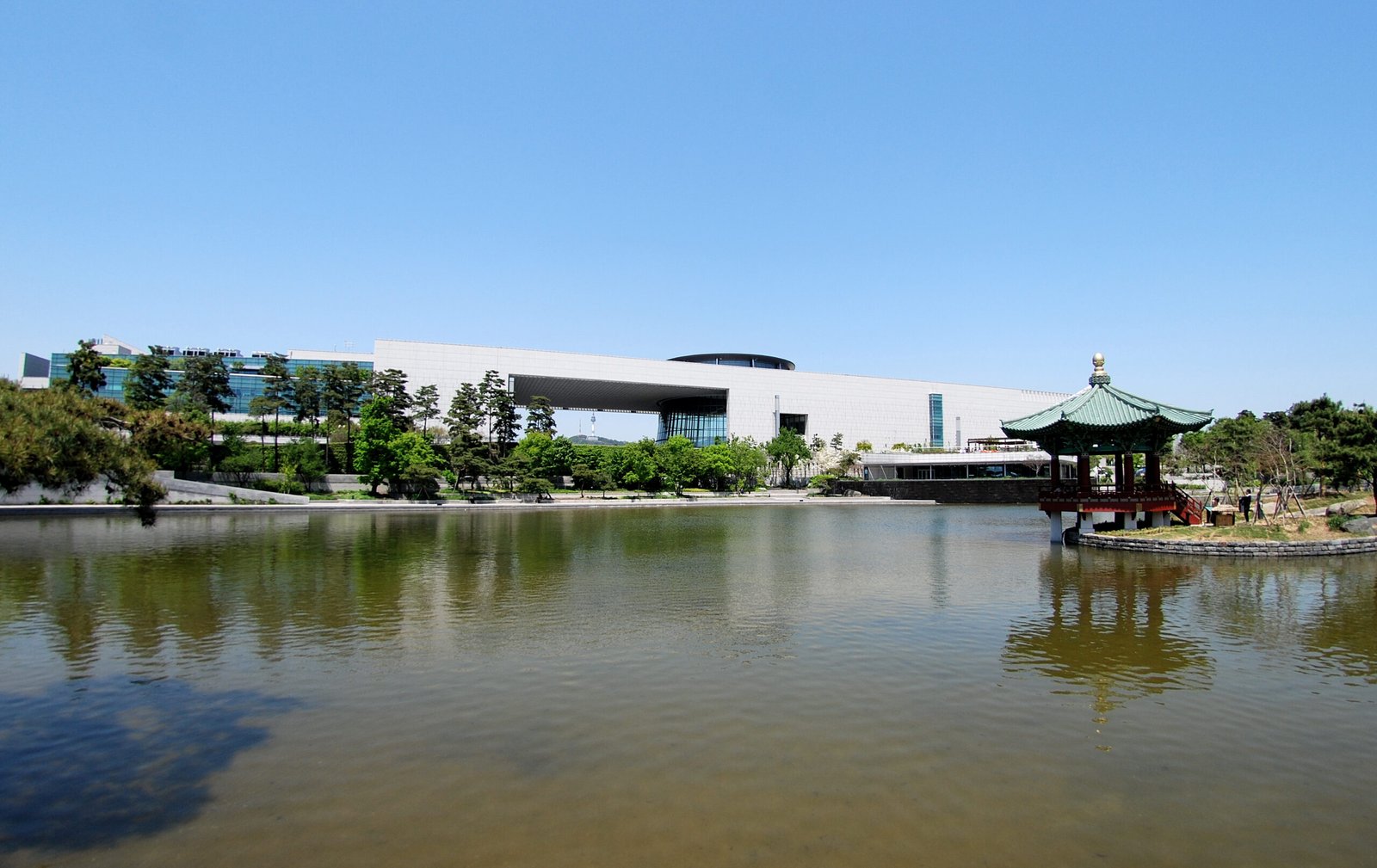 National Museum of Korea building reflected in the Mirror Pond with N Seoul Tower visible through the gap