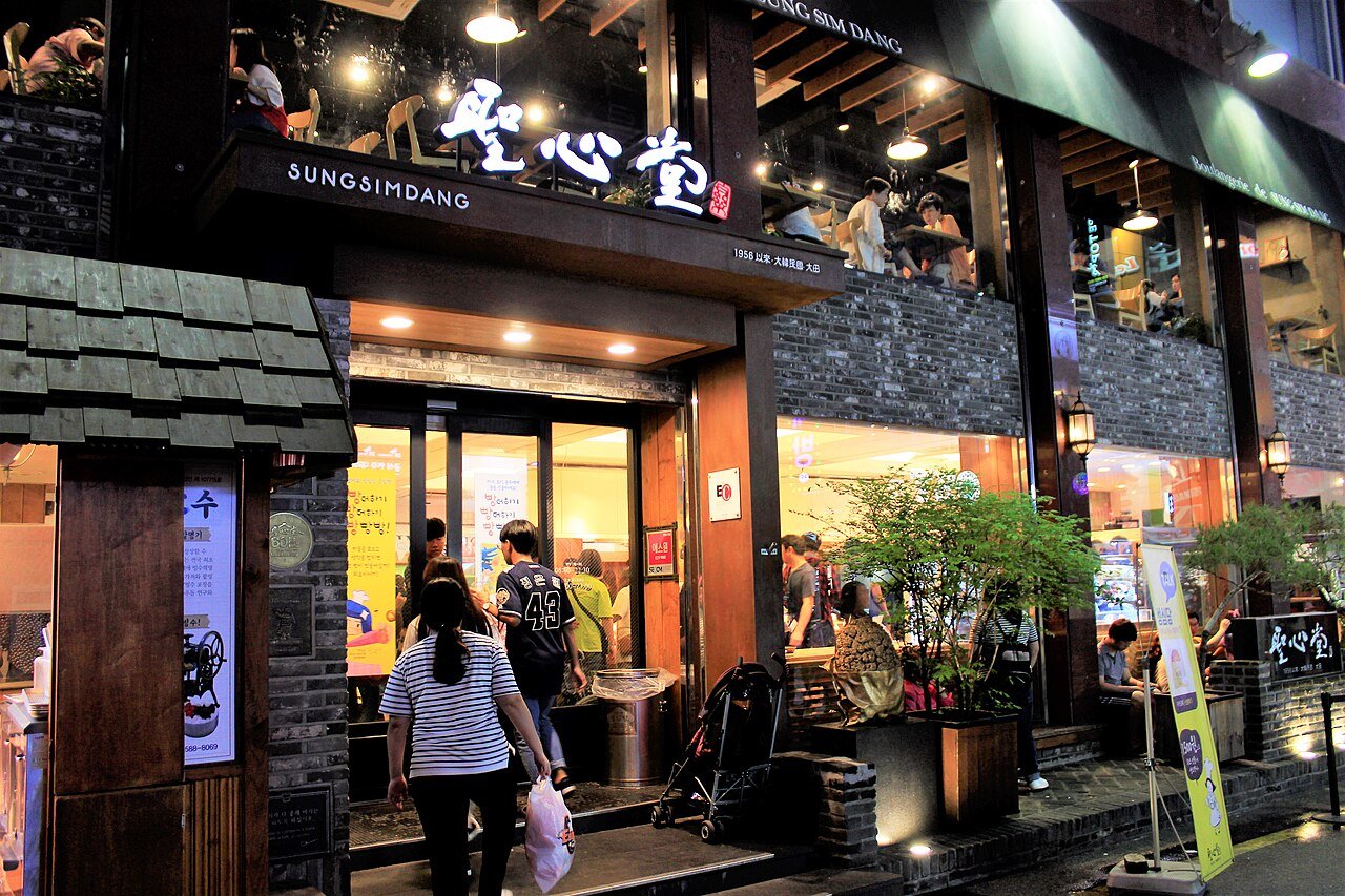 The Sungsimdang main store in Daejeon at night, its Chinese-character sign lit above the entrance