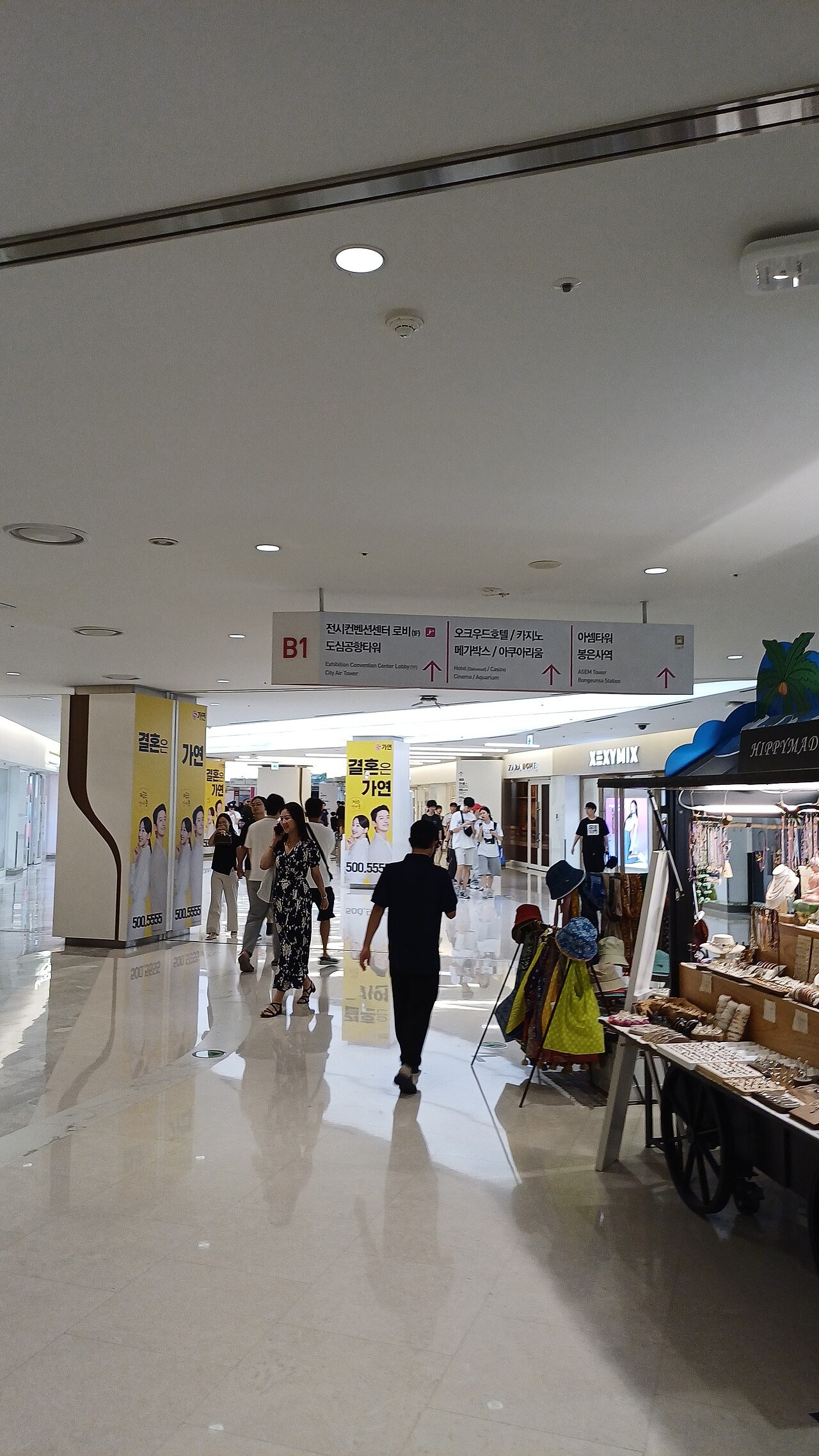 A COEX Mall basement corridor with an overhead bilingual sign pointing to the convention centre lobby, City Air Tower, cinema, aquarium and Bongeunsa Station