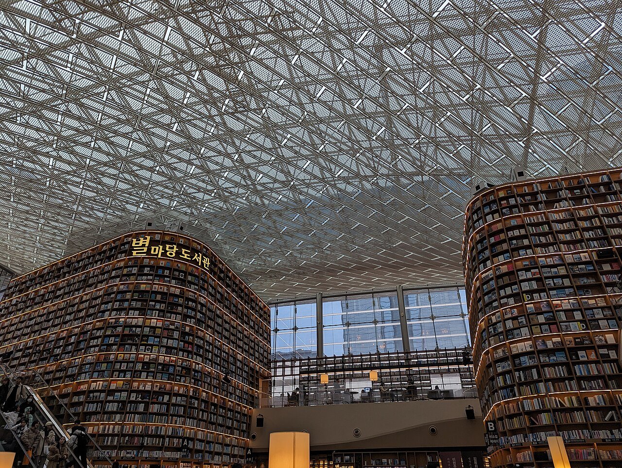 The Starfield Library at COEX, two curved shelf towers rising to a mesh ceiling with reading tables below