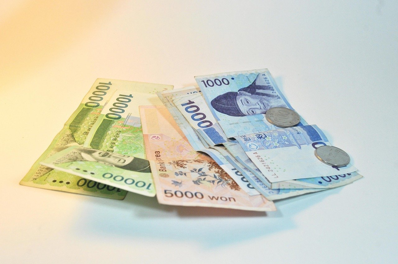 Korean won banknotes and coins spread out on a white surface