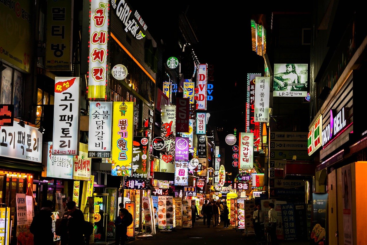 A narrow Seoul street at night lined with Korean neon restaurant signs
