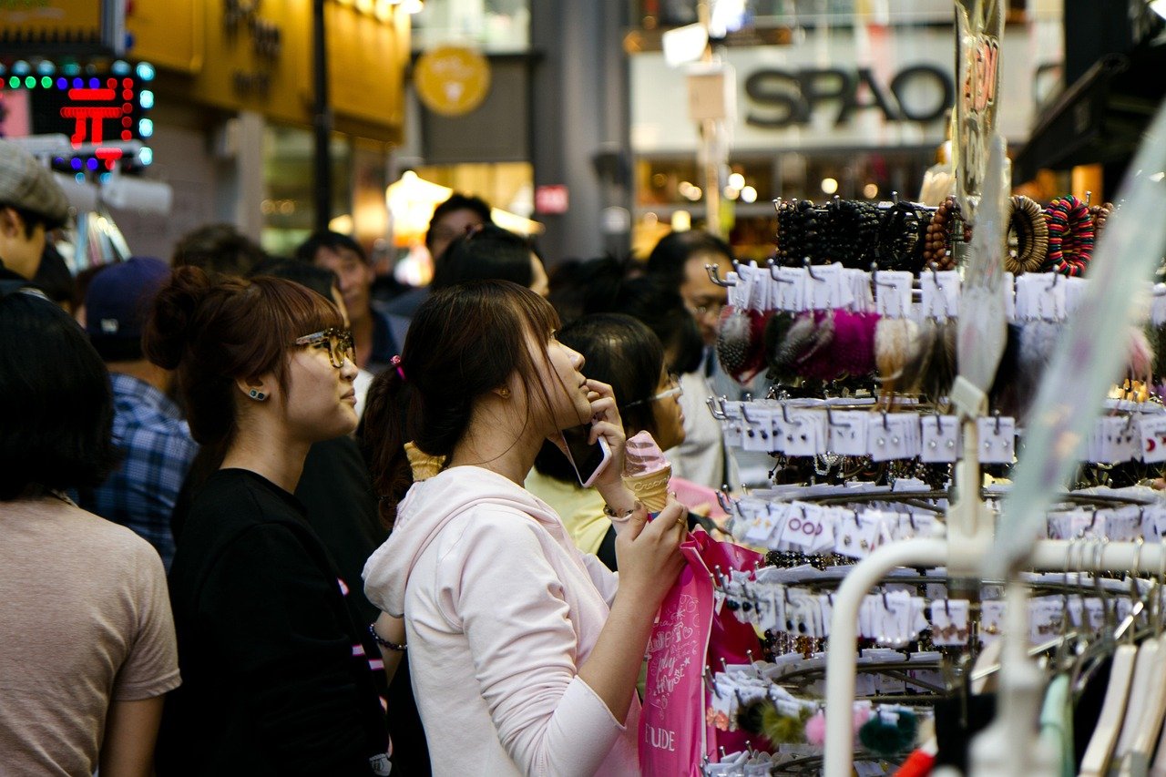 Shoppers browsing accessory stalls on a crowded Korean shopping street