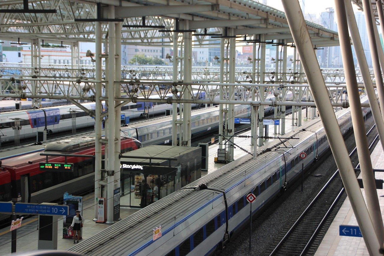 KTX trains waiting at platforms in a large Korean station with a platform number sign and a traveller with a suitcase
