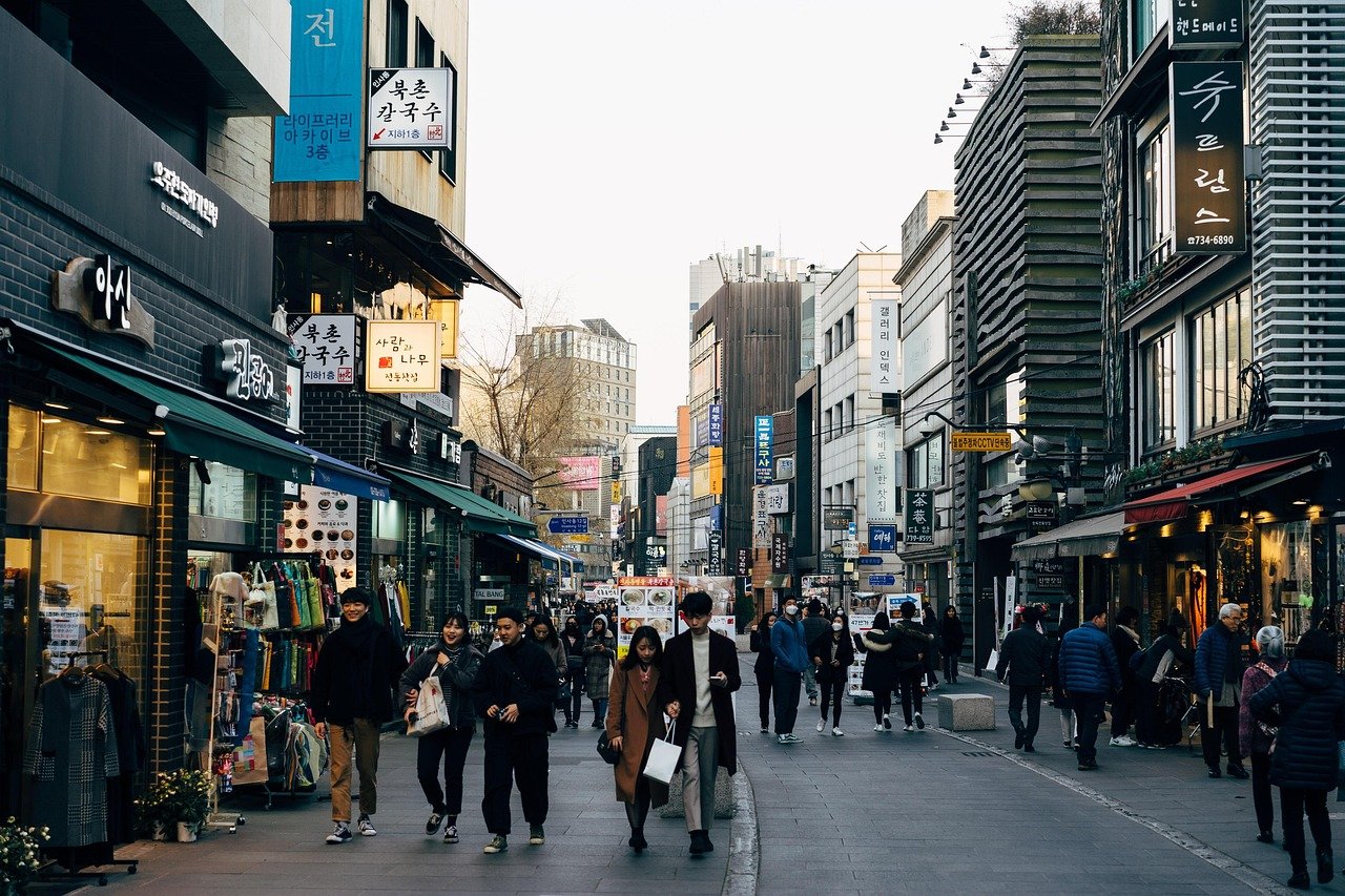 Shoppers walking down a busy Seoul shopping street lined with stores