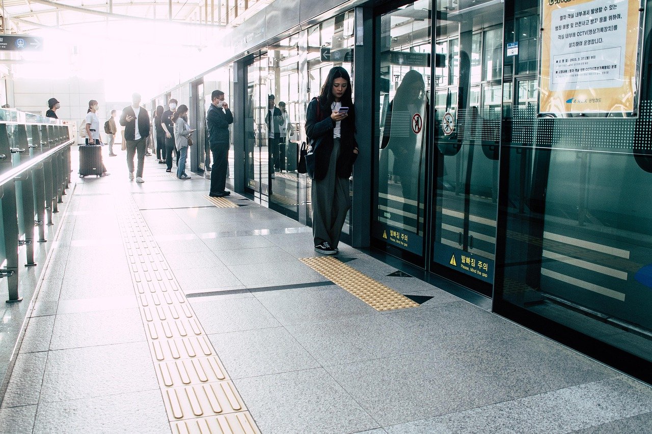 Traveler with a rolling suitcase waiting on a Seoul subway platform